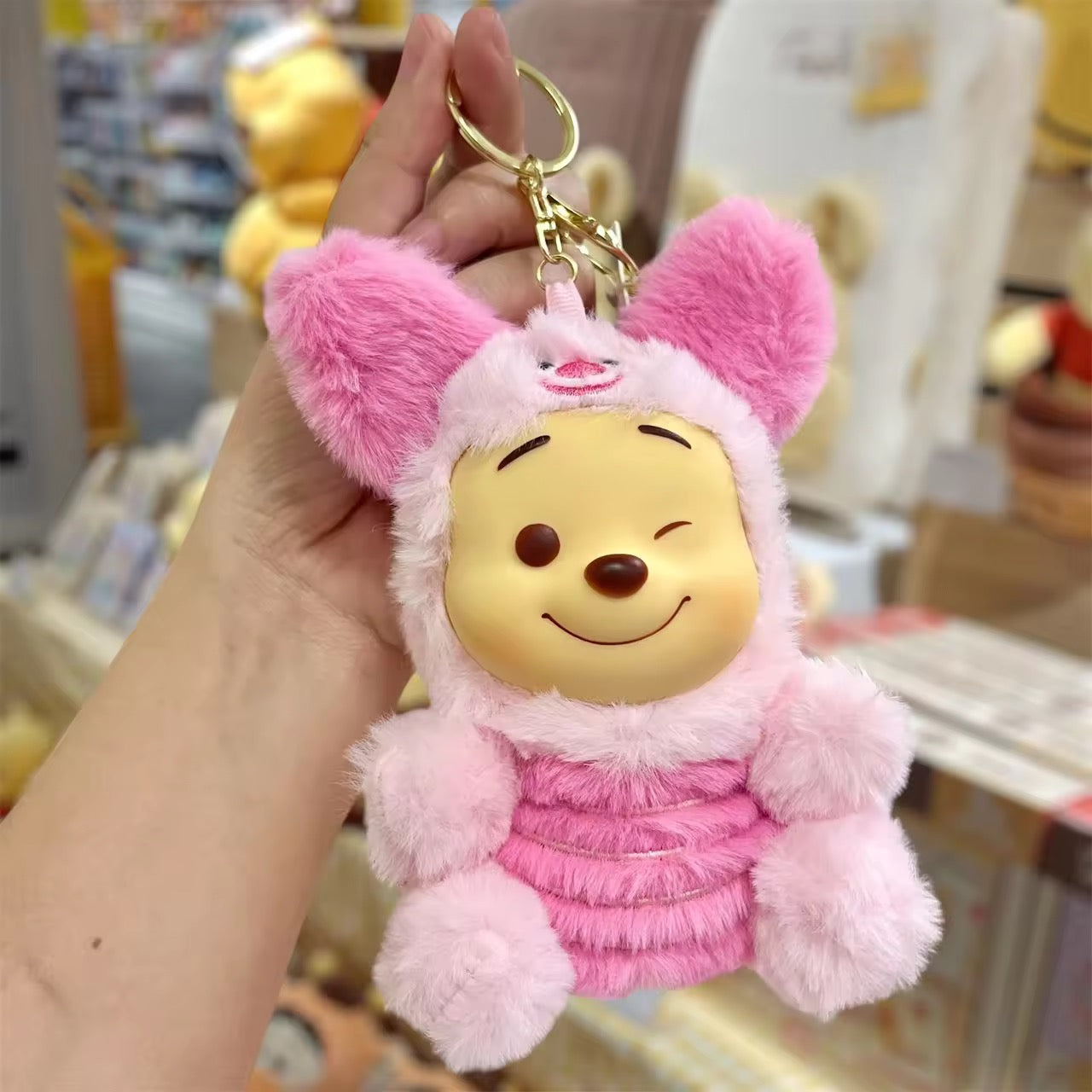 Winnie Pooh keychain featuring a plush figure with a red shirt and smiling face, attached to a metal keyring.